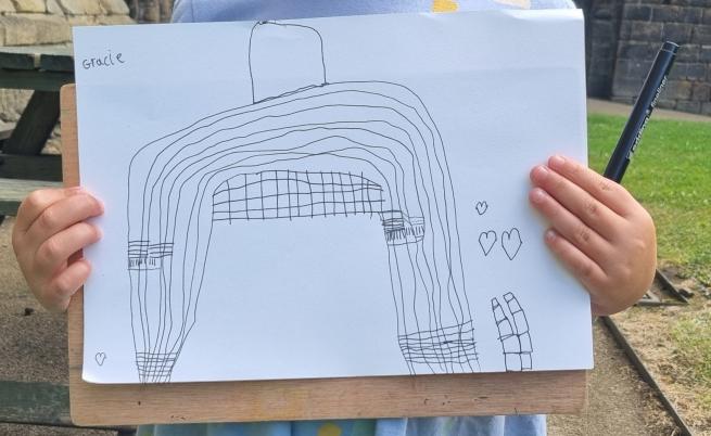 Photograph of a child holding up their drawing