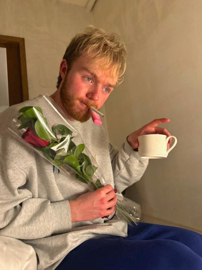 Finley Christie holding a red rose and a cup of coffee/tea/wine