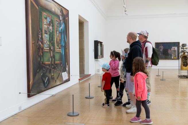 A family looking at a painting hung in a gallery exhibition space