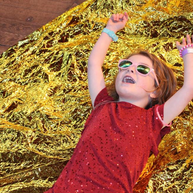 Toddler wearing sunglasses, surrounded by tinsel 
