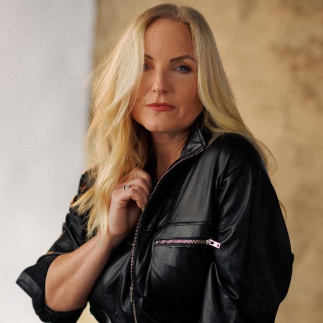 Kerry Ellis casually holds the collar of her black leather bomber jacket.