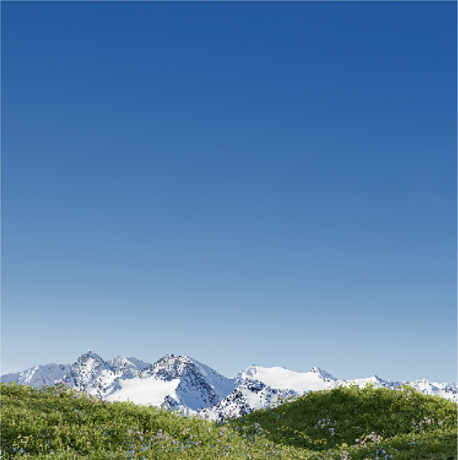 Picturesque landscape of snow-capped mountains and luscious green grass with clear blue sky.