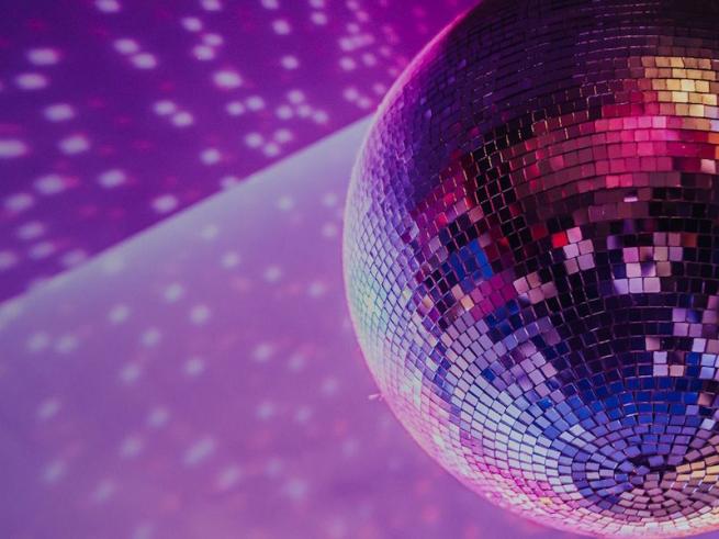A mirror-ball illuminated by purple and blue light casting a colourful light pattern.