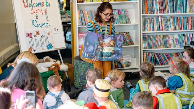 A person showing a group of children a story 