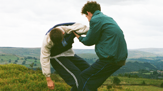 2 male dancers in tracksuits dance in countryside