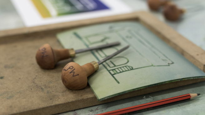 Lino cutting tools on a piece of lino with a design of a building