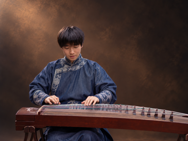 Mio and Guzheng, He is seated wearing traditional outfit
