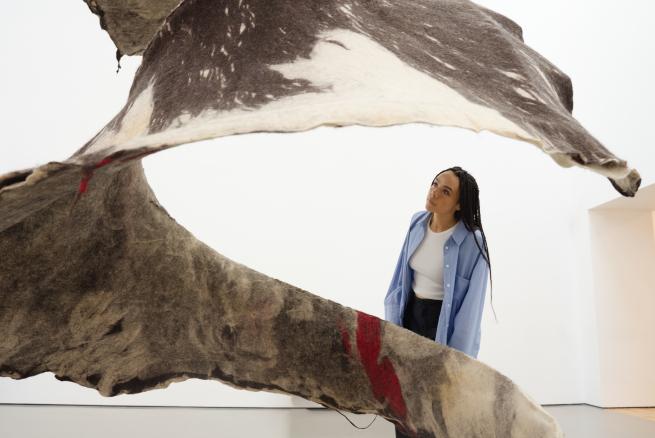 A visitor looks closer at the large fabric spiral-shaped sculpture 'Dancer'.