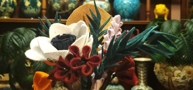 A photograph of multi-coloured felt flowers photographed in Abbey House Museum's Art Furnisher display in front of Burmantofts Pottery