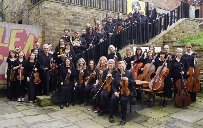 A group of people dressing in black, stood and sat in a group holding musical instruments
