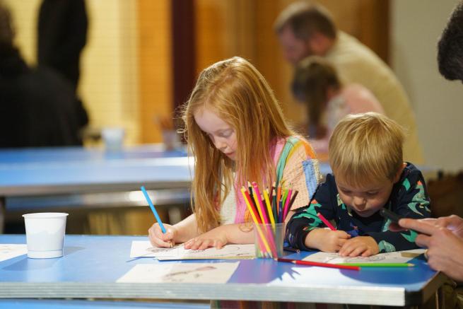 Two children colouring on a blue table