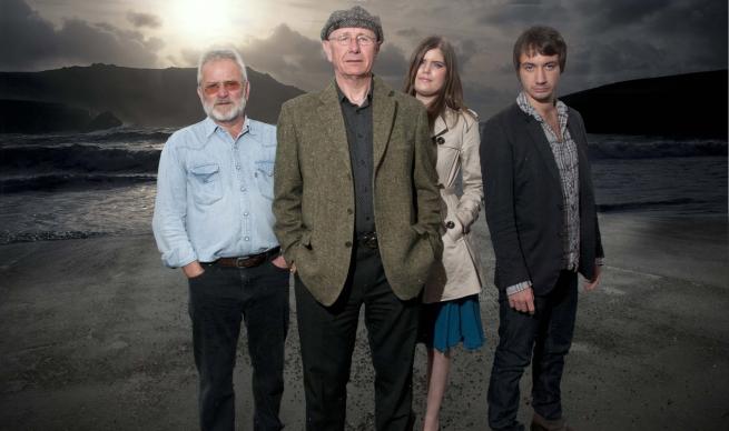 Tom and his band of three other musicians stand proudly on a beach with the sea behind them, they'd better not hang about there too long the tide's coming in, I can tell the phases of the moon too 