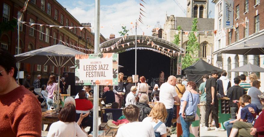 an outdoor scene of people listening to music played on a stage