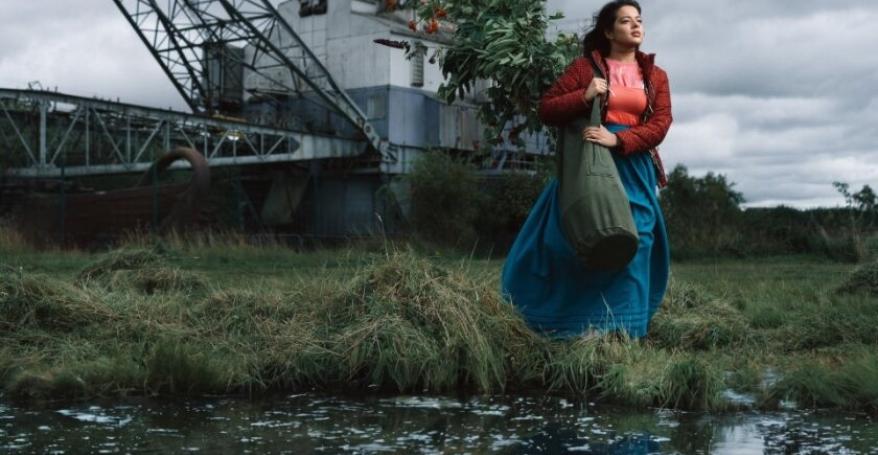 a young woman stands looking in the distance by water