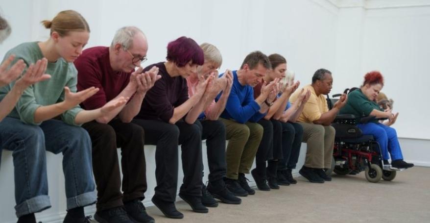 People sit in a row with heads in hands