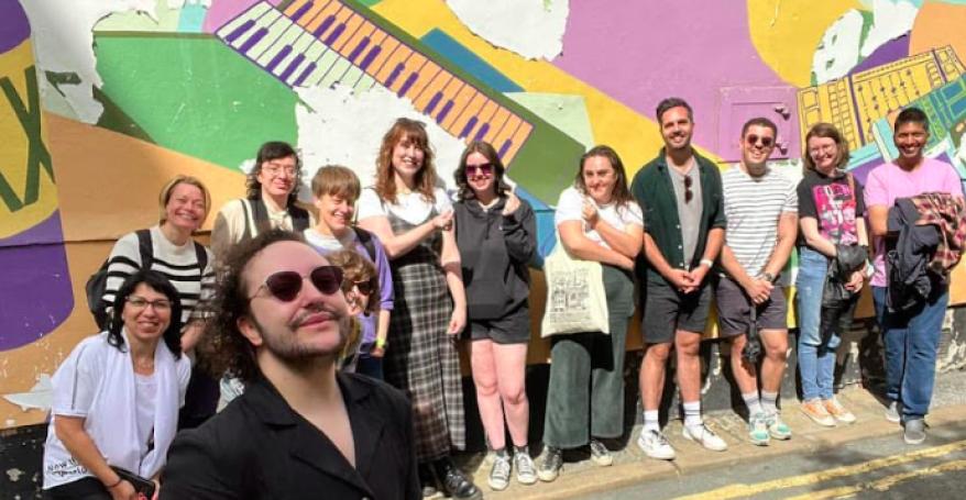 A group of people stand in front of a mural