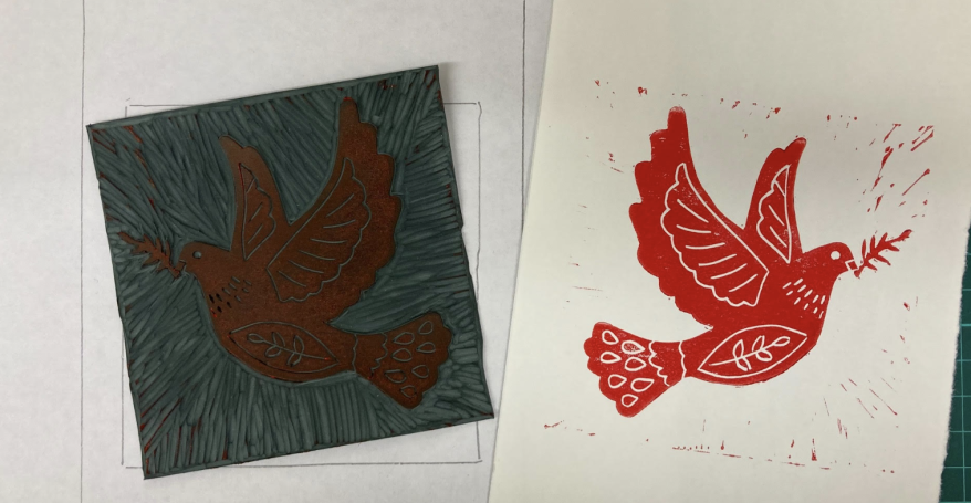 A lino printed dove in red ink, next to the piece of lino the print was taken from.