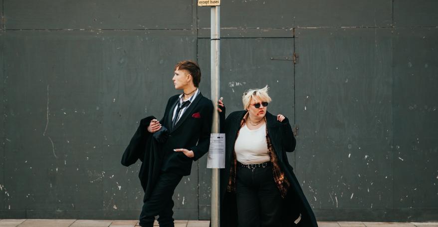 Two goths standing at a bus stop