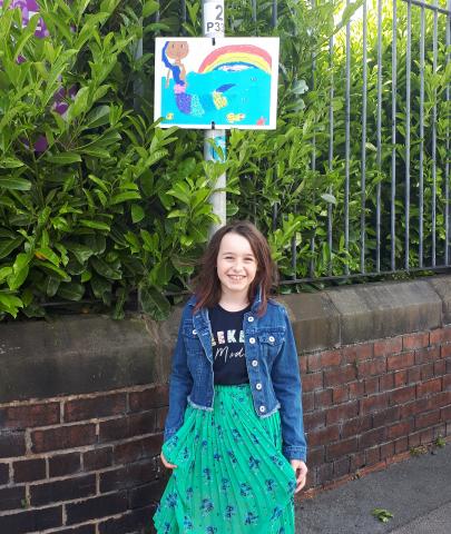 little girl standing in front of a lamp post underneath her picture she drew