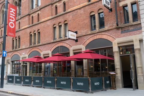 Exterior of a restaurant with pavement tables covered by red parasols