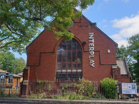 A photo showing the outside of Interplay Theatre, it is a red brick building which is a converted old church hall