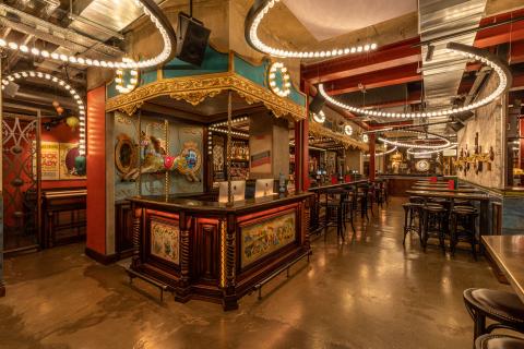 An image of the bar in Flight Club Leeds with a dartboard play space in the background.