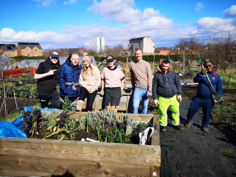 A group of smiling people stood behind a raised bed at Lady Pit Lane Allotments