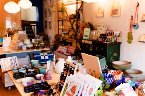 Interior of the retail space of stocked. showcases prints, ceramics, homewares and jewellery on tables