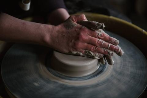 Hands working clay on a potter's wheel.