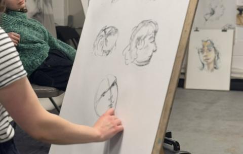 An artist practising portraiture in charcoal