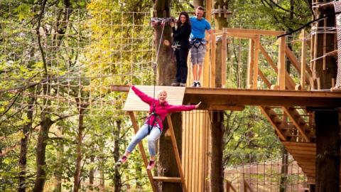 Lady wizzing down one of our many zipwires on out Tree Top Adventure course.