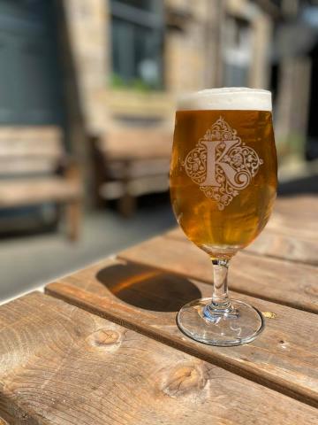 Pint of beer on a table in a glass marked with the letter K.