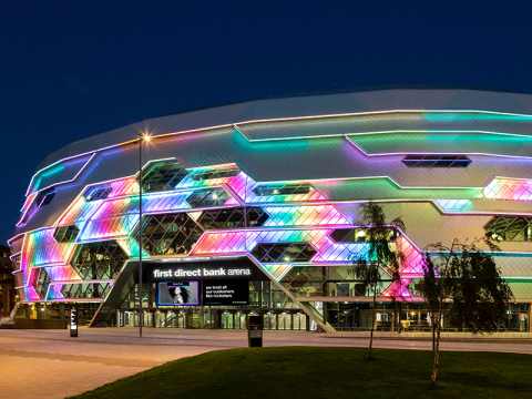 first direct bank arena glowing multicoloured at night.
