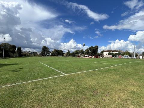 a large grass football pitch with small stands around