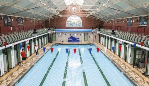 a large indoor swimming pool with bunting of blue white and red around the edges