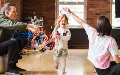 A toddler runs through colourful ribbons