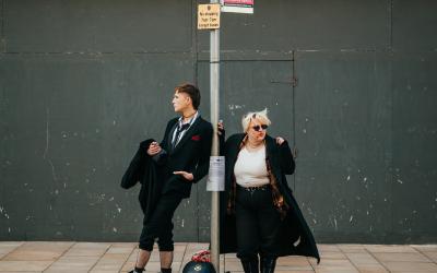 Two goths standing at a bus stop