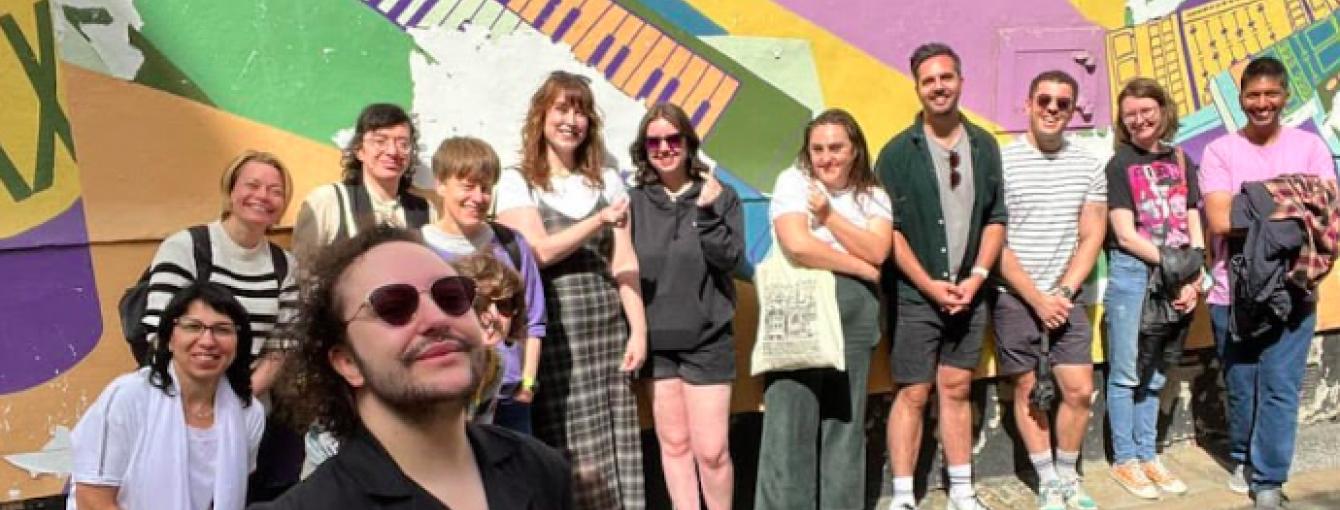 A group of people stand in front of a mural