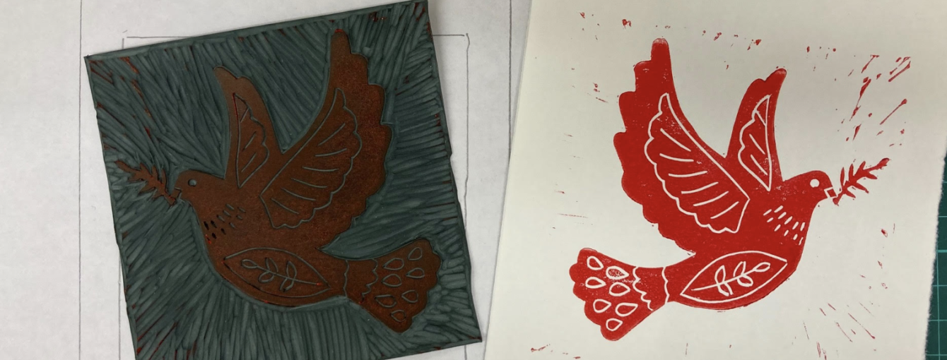 A lino printed dove in red ink, next to the piece of lino the print was taken from.