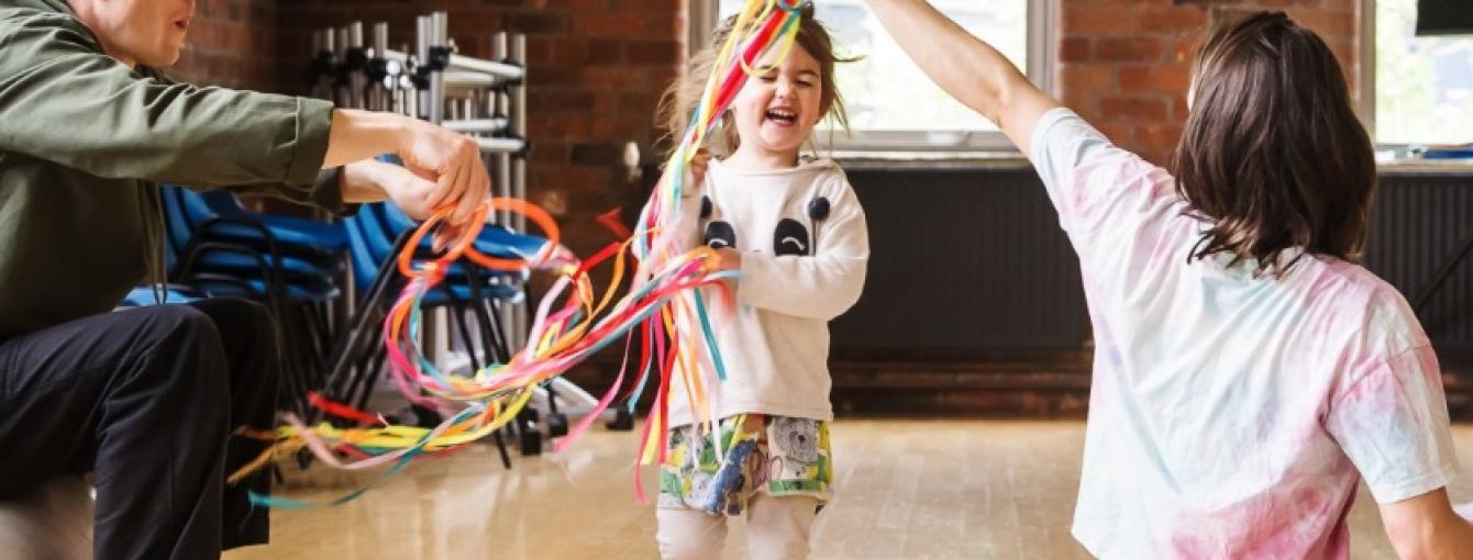 A toddler runs through colourful ribbons
