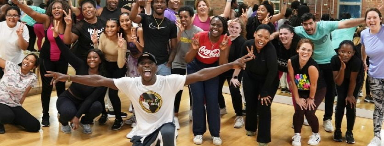 A group of people wave to the camera in a dance studio