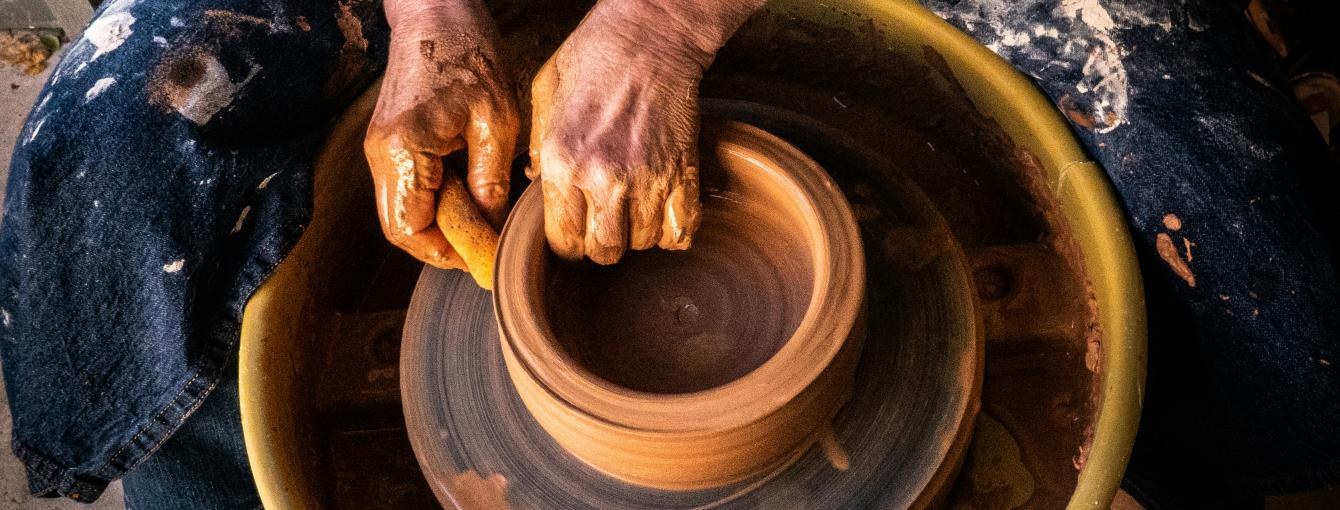 A lady at a pottery wheel making a ceramic pot